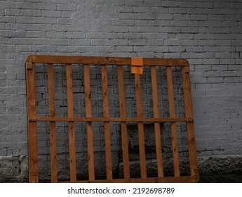 Old Dumped Chucked Thrown Away Wooden Bed Frame On Street Brick Wall Background 