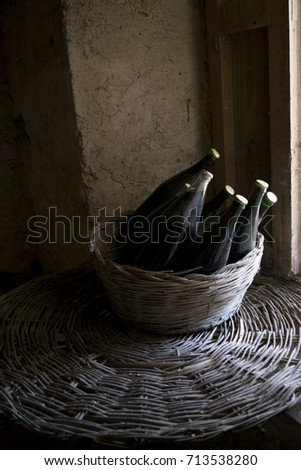 old and dusty botlles of aged red wine in a wicker basket illumined through a window