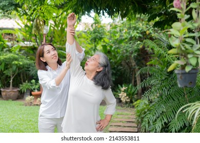 An Old Elderly Asian Woman And Exercise In The Backyard With Her Daughter.  Concept Of Happy Retirement With Care From A Caregiver And Savings And Senior Health Insurance, Happy Family