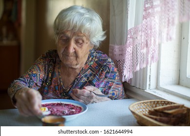 An Old Elderly Woman Eating Soup Borsch Sitting At The Table.