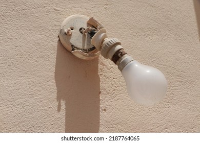 Old Electric Lamp On The Yellow Wall. Ancient And Rusty Electric Articles
