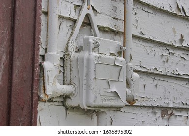 An Old Electrical Box Outside An Abandoned Church With Heavily Peeled White Paint. The Box Reads, 