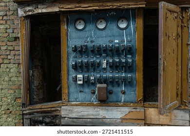 Old electrical control panel with switches meters and peeling paint inside a derelict industrial building