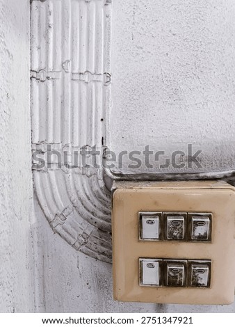 Old electrical light switch panel with visible conduit wiring installed on a concrete wall showing building electrical infrastructure.