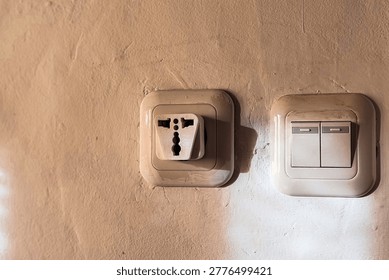 Old Electrical Outlet and Light Switch on Worn Wall Showing Unsafe Home Installation