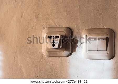 Old Electrical Outlet and Light Switch on Worn Wall Showing Unsafe Home Installation