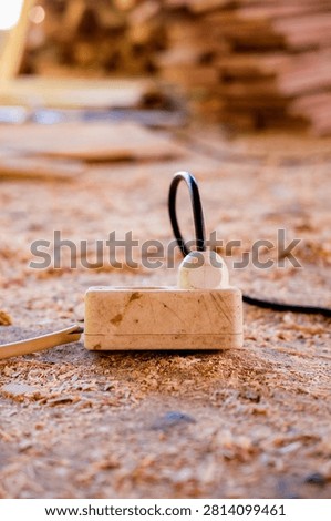 Old Electrical Power Strip and Cable on Wood Shavings in a Traditional Furniture Workshop