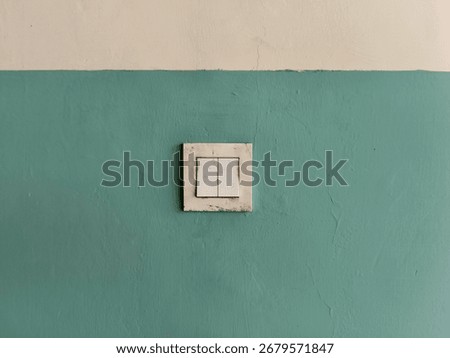 Old electrical socket and light switch on a green painted wall, showing signs of dirt and wear, suitable for background, texture, or utility concept.