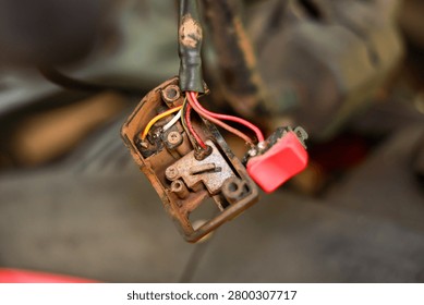 Old electrical switch red button exposed wire metal rust corrosion damaged closeup repair maintenance machinery industrial worn dirty mechanical technology connection circuit component tool