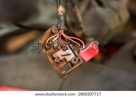 Old electrical switch red button exposed wire metal rust corrosion damaged closeup repair maintenance machinery industrial worn dirty mechanical technology connection circuit component tool