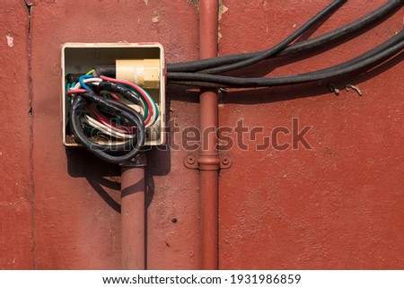 Old elextrical socket box junction wiring and a cover is missing on the cenent wall.