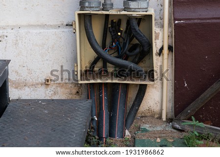 Old elextrical socket box junction wiring and a cover is missing on the cenent wall.
