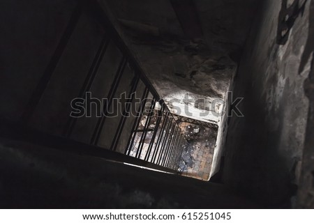 Old empty abandoned bunker interior with rusted metal ladder going down from dark room