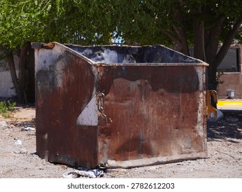 An old empty garbage container in bad conditions, placed near a street