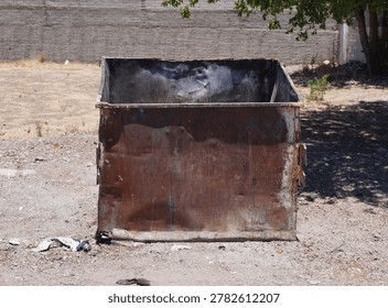 An old empty garbage container in bad conditions, placed near a street