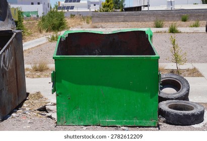 An old empty garbage container in bad conditions, placed near a street