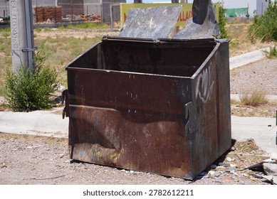 An old empty garbage container in bad conditions, placed near a street