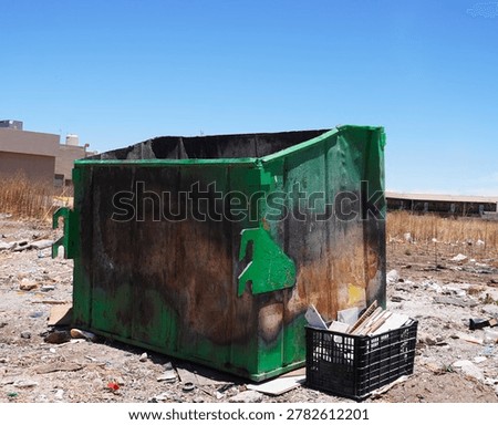 An old empty garbage container in bad conditions, placed near a street