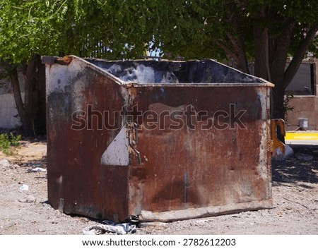 An old empty garbage container in bad conditions, placed near a street
