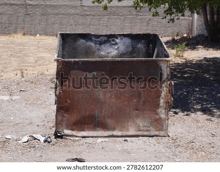 An old empty garbage container in bad conditions, placed near a street