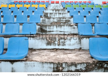 Old empty multicolored stadium seats with dirty cement steps