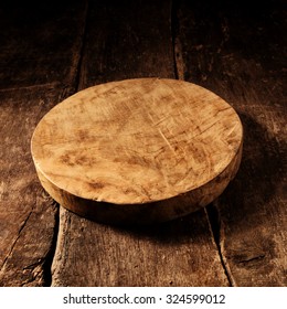 Old Empty Round Rustic Wooden Cheese Board With Deeply Scored Cuts And Stains On A Rustic Wooden Table With Copyspace For Your Placement Of Products Or Advertising