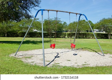 An Old Empty Swingset Above A Sand Pit In An Outdoor Park.