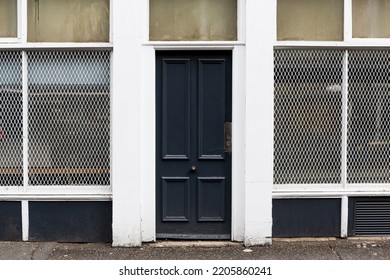 Old Empty Urban Inner City Shop Facade Featuring Black Wooden Door And White Security Grilles