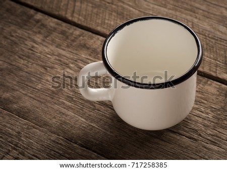 Old enamel empty cup on a wooden surface