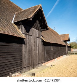 Old English Farm Barn. The Exterior Of An Old Timber Barn On An English Farm In The Bright Spring Sunshine.