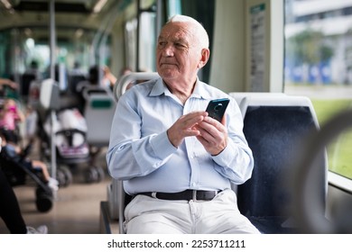 Old European man sitting in streetcar and using smartphone while waiting for next stop. - Powered by Shutterstock