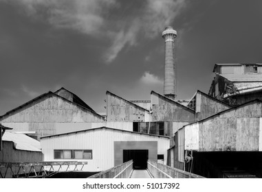 Old Factory Exterior With Buildings And Chimney.