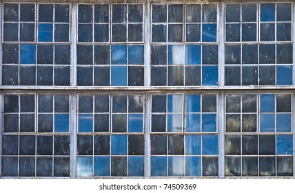Old factory windows texture with blue sky reflections