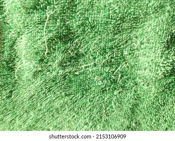 Old faded towel texture background. Pale green color terry cotton towel close up. Household bath toweling cloth. Used towel closeup texture