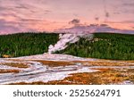 Old Faithful Geyser eruption at sunset in Yellowstone National Park. UNESCO world heritage in Wyoming, United States