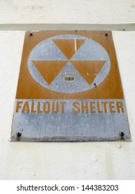 Old Fallout Shelter Sign from the cold war era slowly rusts as it hangs on wall.