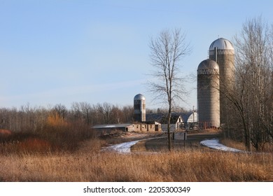 Old Farm Country Road In Winter With The Sun Setting On Dry Brush With Snow Along The Road To The Silo