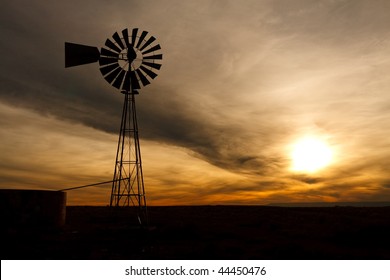 Old Farm Windmill for Pumping Water with Spinning Blades at Sunset in New Mexico, USA