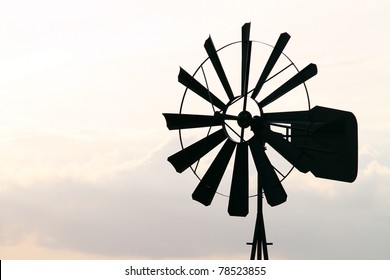 Old Farm Windmill for Pumping Water with Spinning Blades at Sunset in New Mexico, USA