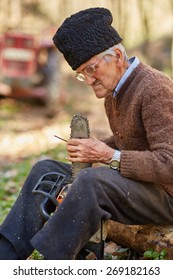 Old farmer doing maintenance work to his chainsaw