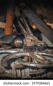 Old Farrier Tools Together With Some Horse Shoes Are Displayed On Vintage Wood.