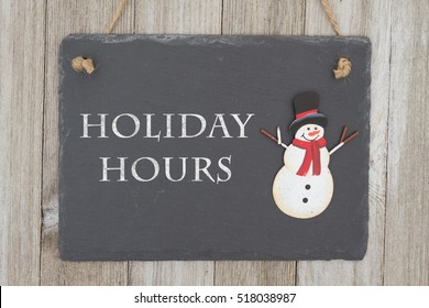 Old Fashion Christmas Store Message, A Retro Chalkboard With A Snowman Hanging On Weathered Wood Background With Text Holiday Hours