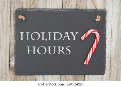 Old Fashion Christmas Store Message, A Retro Chalkboard With A Candy Cane Hanging On Weathered Wood Background With Text Holiday Hours