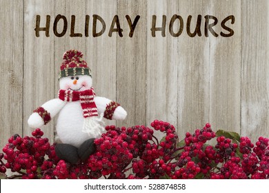 Old Fashion Christmas Store Message, Frost Covered Red Holly Berries With A Snowman On Weathered Wood Background With Text Holiday Hours