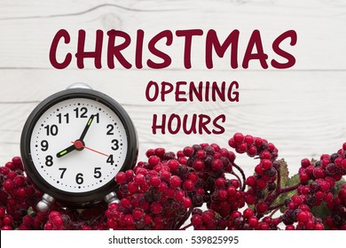 Old Fashion Christmas Store Message, Frost Covered Red Holly Berries With An Alarm Clock On Weathered Wood Background With Text Christmas Opening Hours