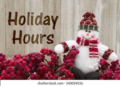 Old Fashion Christmas Store Message, Frost Covered Red Holly Berries With A Snowman On Weathered Wood Background With Text Holiday Hours