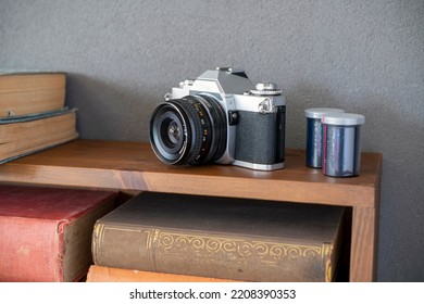 Old fashioned 35mm camera with slide film on bookshelf    