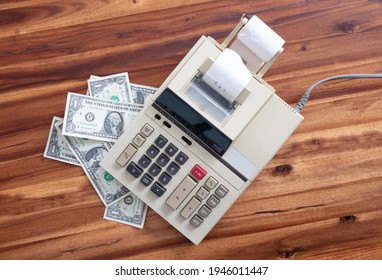 Old fashioned calculator and dollars on a desk