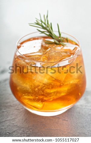 Old fashioned cocktail in a glass with ice and rosemary