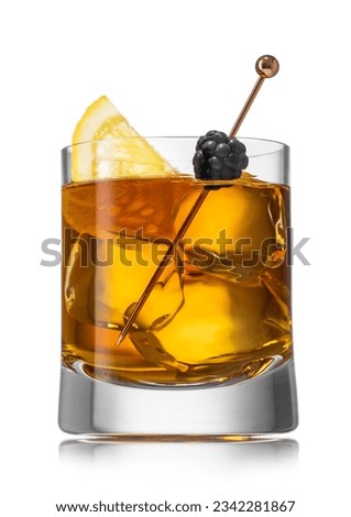Old fashioned cocktail in homemade glass with ice cubes and blackberry with orange slice on white.